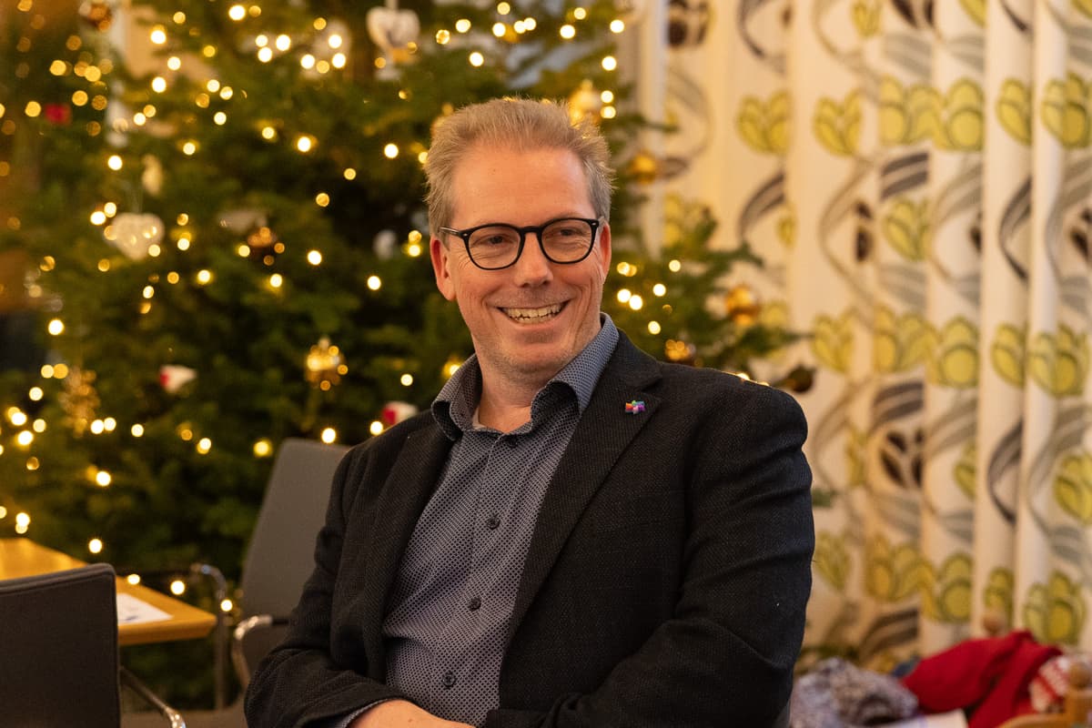 Tom Anders Stenbro Smilende mann med briller sitter foran et juletre