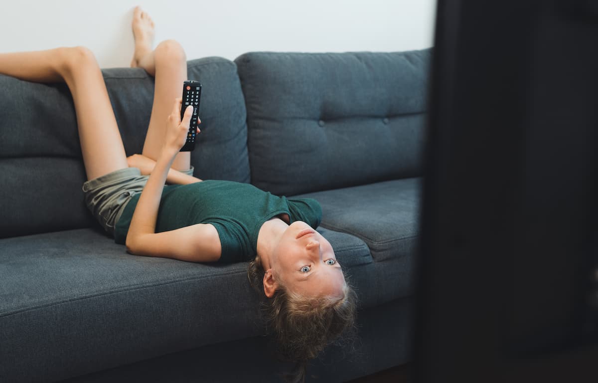 Alene etter skoletid Jente ligger oppned i sofaen og ser på tv