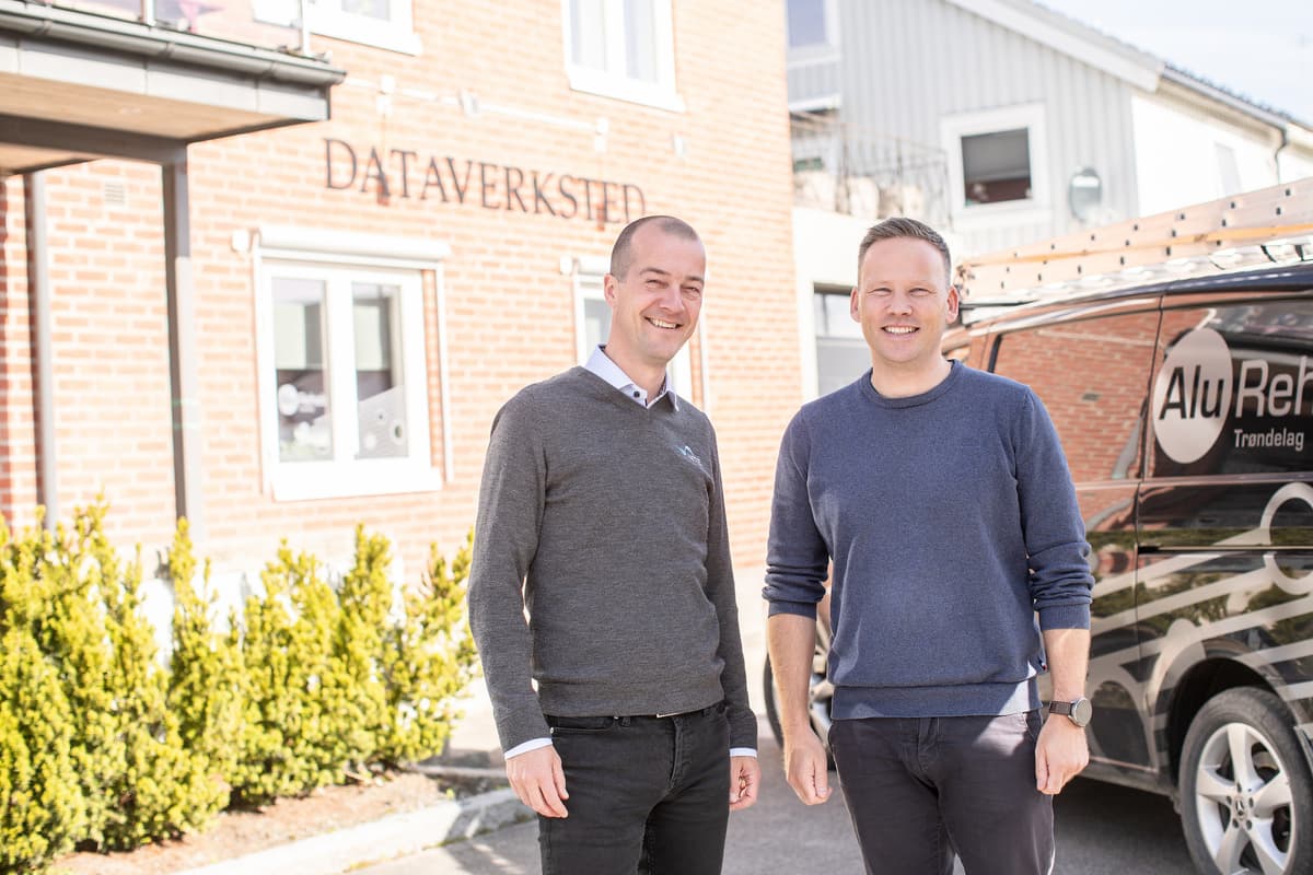 Morten Resve og Tore Forbord i Alu Rehab To smilende menn utenfor en bygning hvor det står dataverksted på veggen.