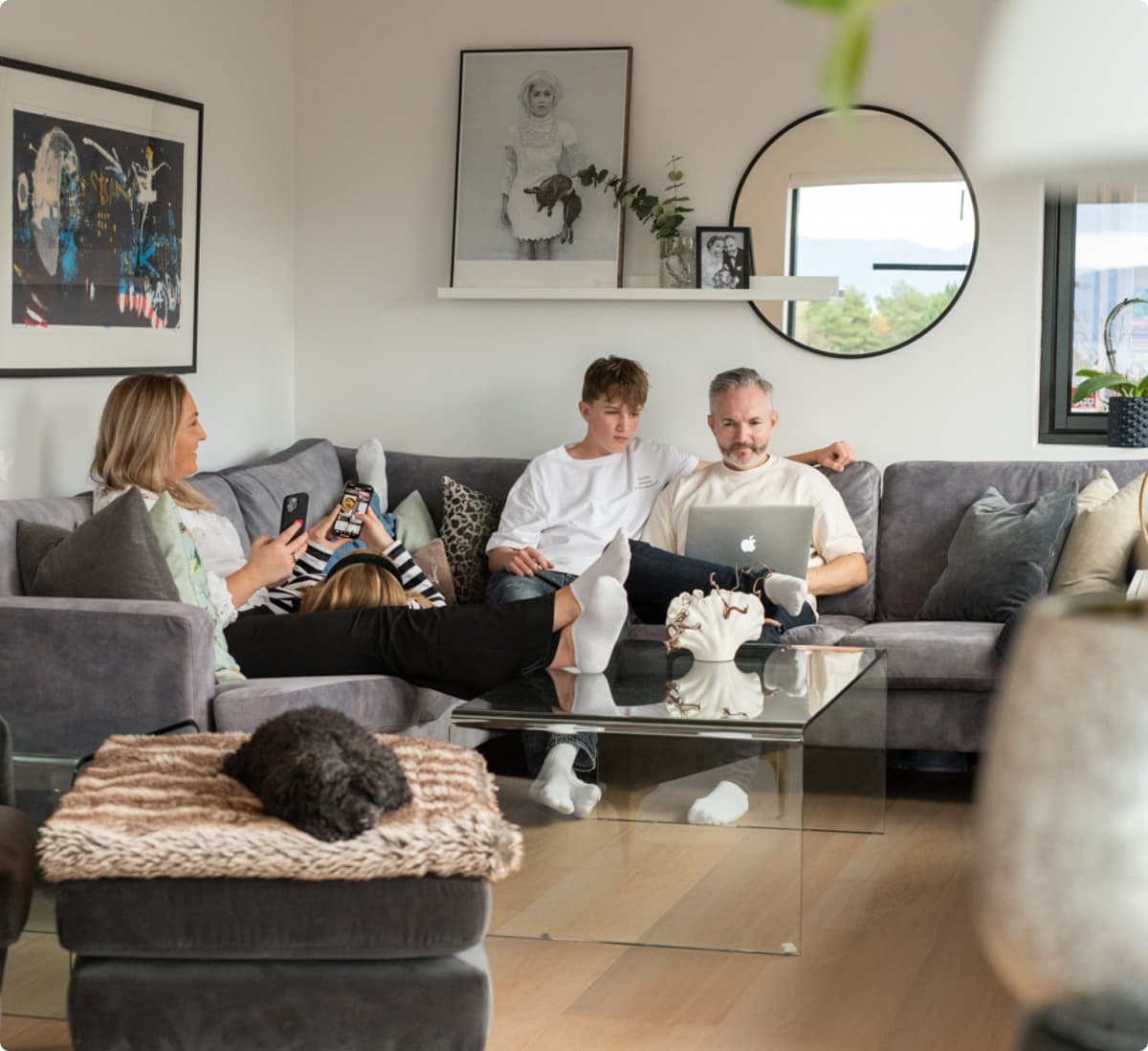 Familie Altibox husstand Familie som sitter i sofa i en stue med hver sin enhet