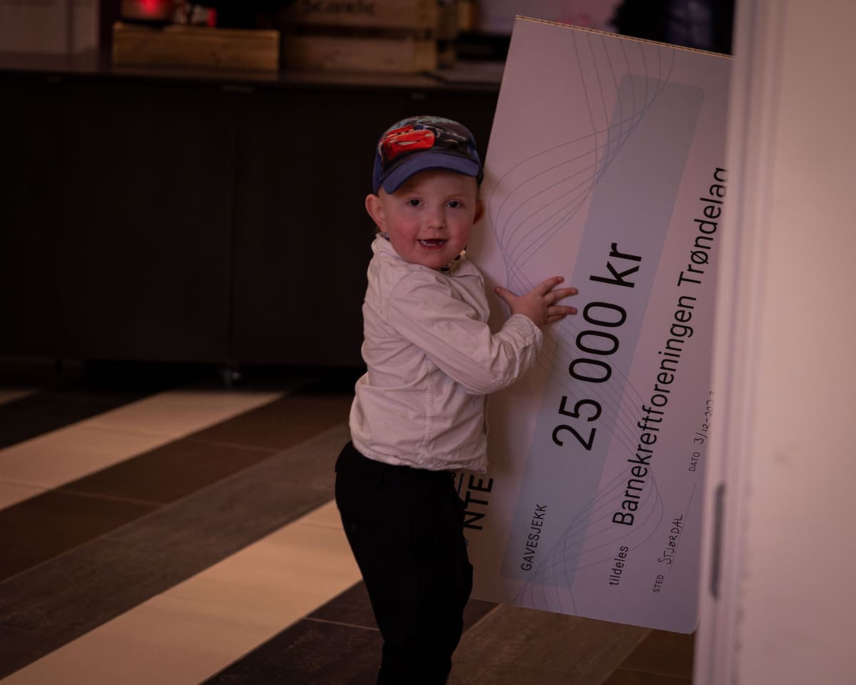 markus leker med sjekken Guttunge med caps leker med en sjekk på 25 000 kroner