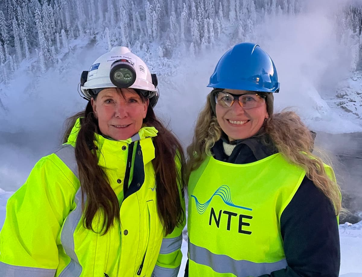 ordførere i fiskumfoss To kvinner i verneklær og hjelmer foran en foss og snødekte trær