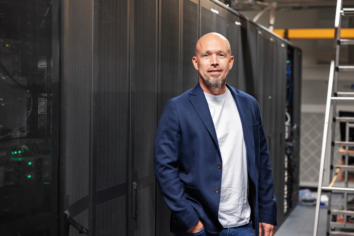 Stian Kilaas Smilende mann i dressjakke foran en lang rekke med skap