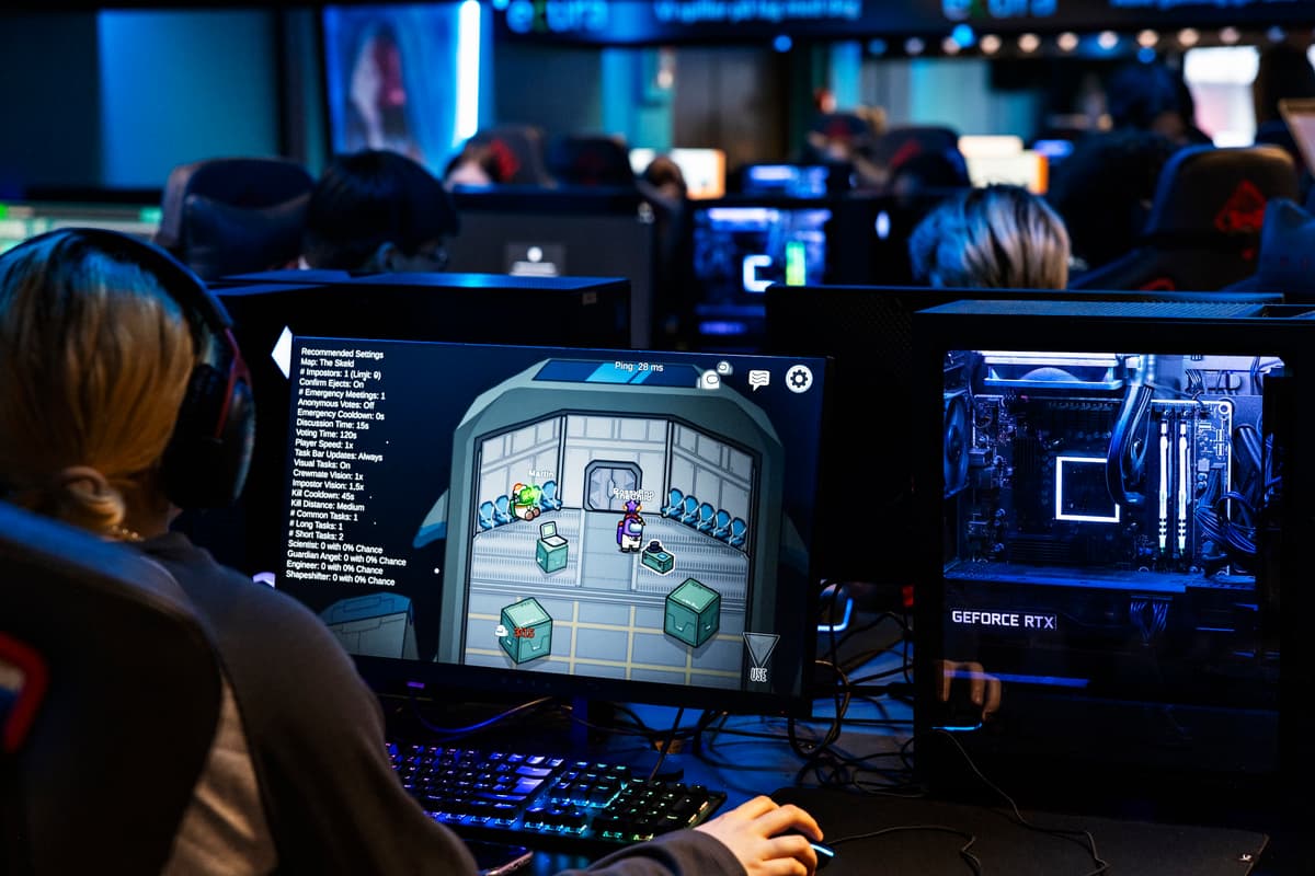 spillere Ryggen på en ungdom som sitter på en skjerm og gamer. Foran henne sitter mange andre ungdommer og gjør det samme.