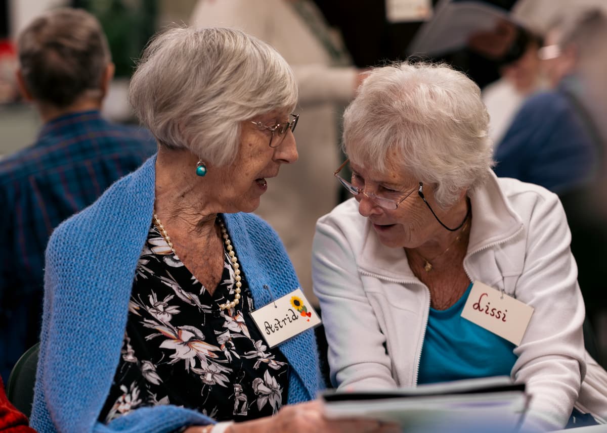 To venninner To eldre damer sitter tett sammen og snakker