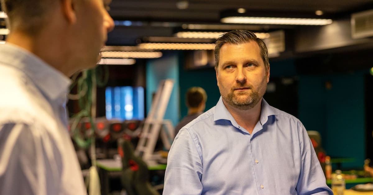 Tommy Pedersen Mann i skjorte ser bort på en annen mann