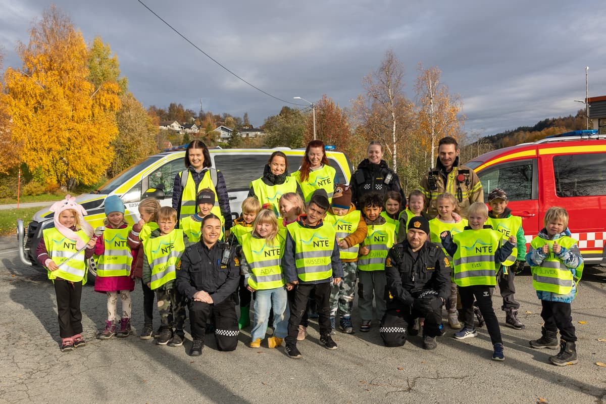 Førsteklassinger, lærere, politi, brann, Trygg Trafikk Barn og voksne med refleksvester foran en brannbil og en politibil