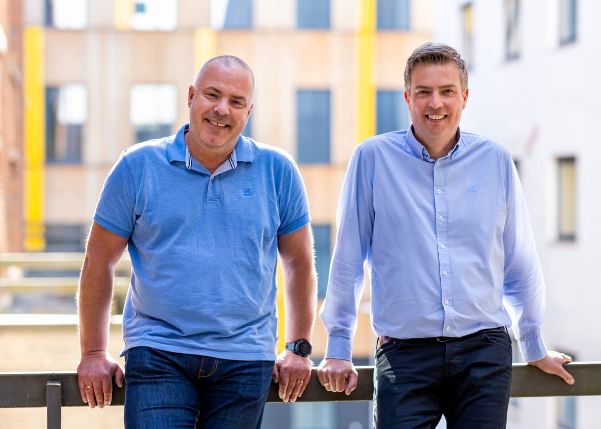 To smilende menn lener seg mot rekkverket på en veranda To smilende menn lener seg mot rekkverket på en veranda