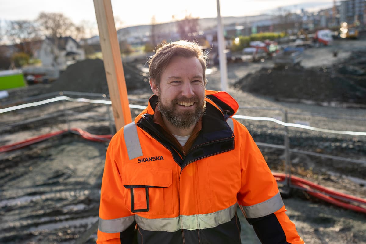 Kim Bundgård Skanska Smilende mann i arbeidsklær foran en byggeplass