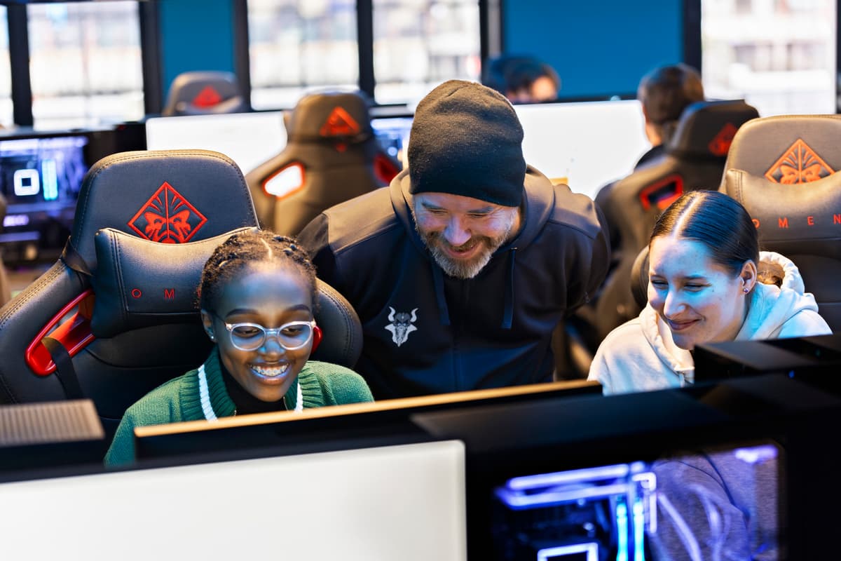 gamere En smilende mann står mellom to glade jenter som gamer