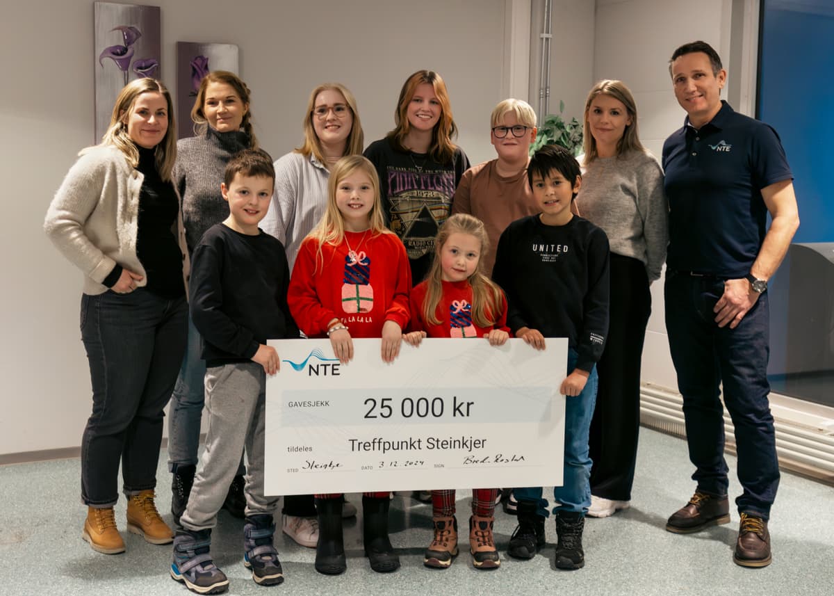 25 000 kroner til Treffpunkt for barn og unge 11 barn, ungdommer og voksne står sammen og holder opp en sjekk på 25 000 kroner.