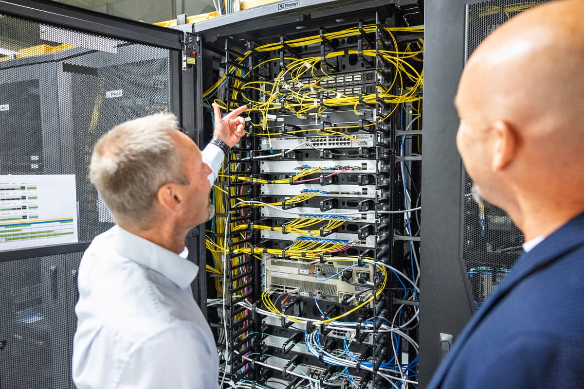 Skap To menn med ryggen til ser inn i et skap fullt av kabler