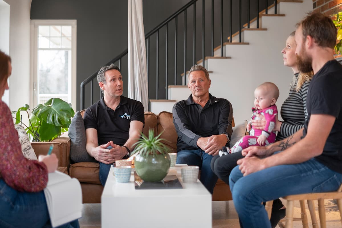 samtale Tre menn, to kvinner og en baby i samtale rundt et stuebord