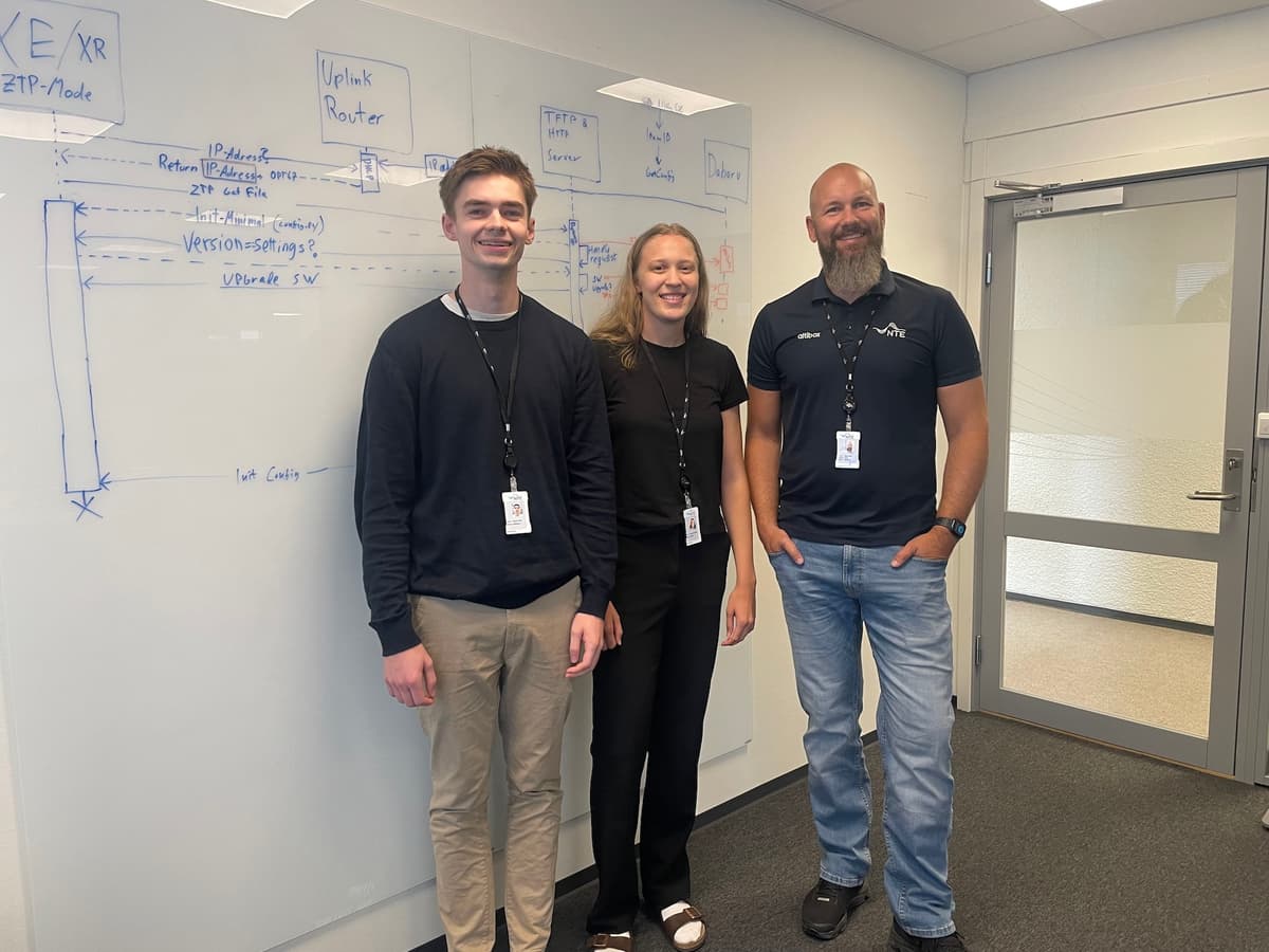 Sommerstudentene Gustav og Regine sammen med Mats Olsen To menn og en kvinne foran en tavle med skrift og tegninger smiler mot deg