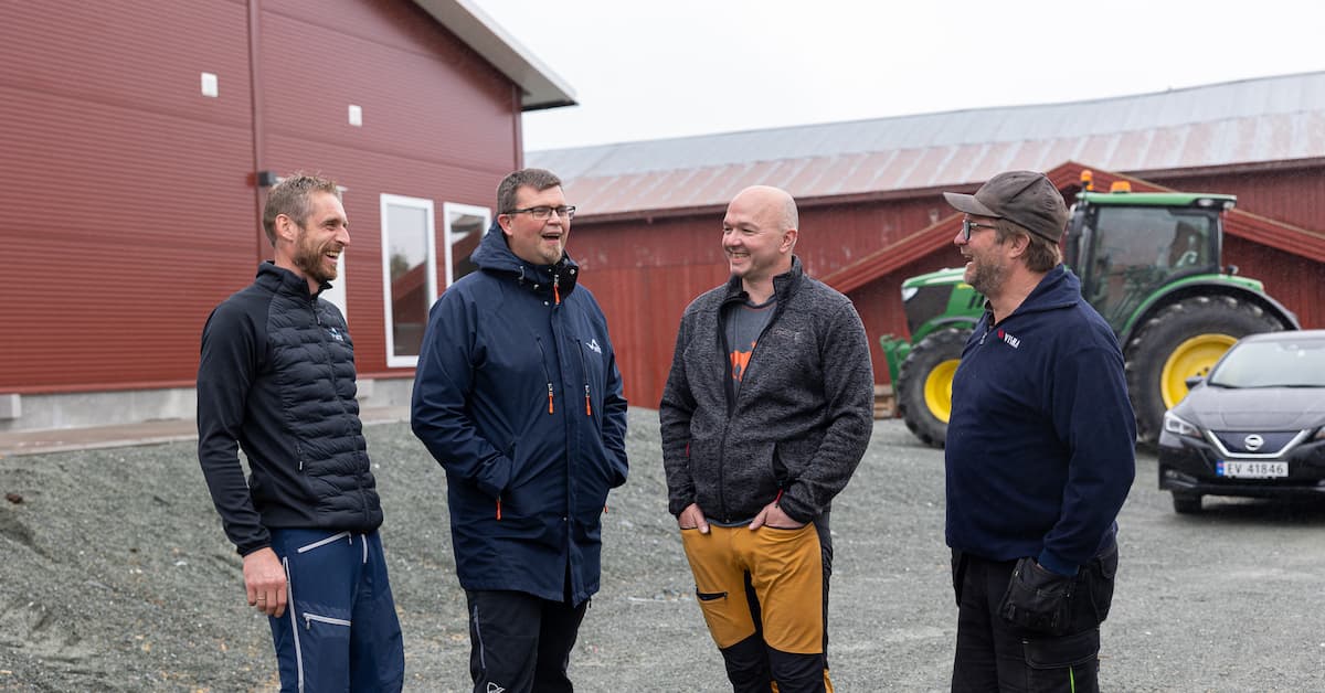 Fire blide menn i samtale foran en traktor