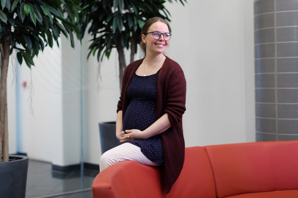 Marianne Rannem Veie Smilende gravid dame sitter på en sofarygg