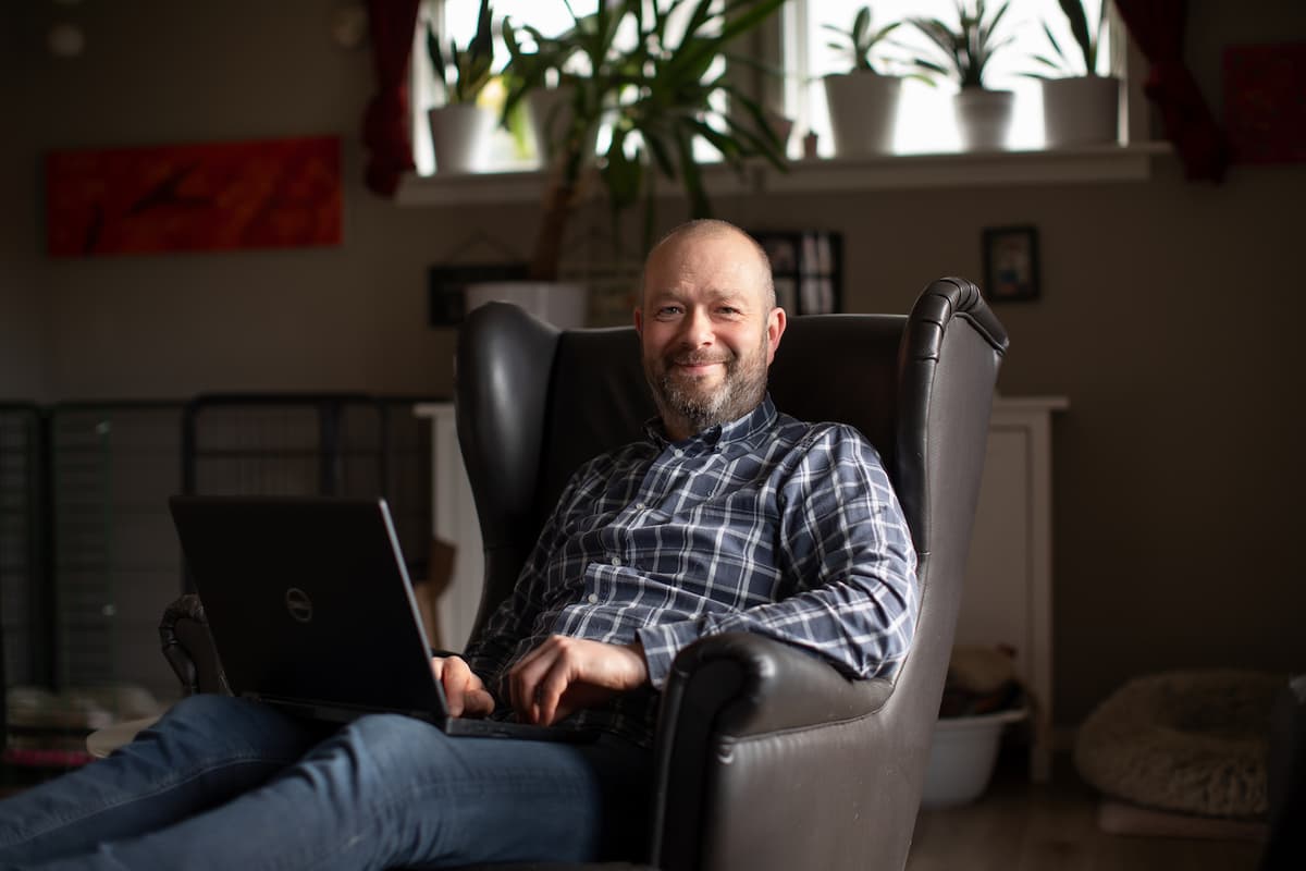 forsidebilde Per-Arvid Wold Mann sitter i en stol med PC-en oppslått på fanget