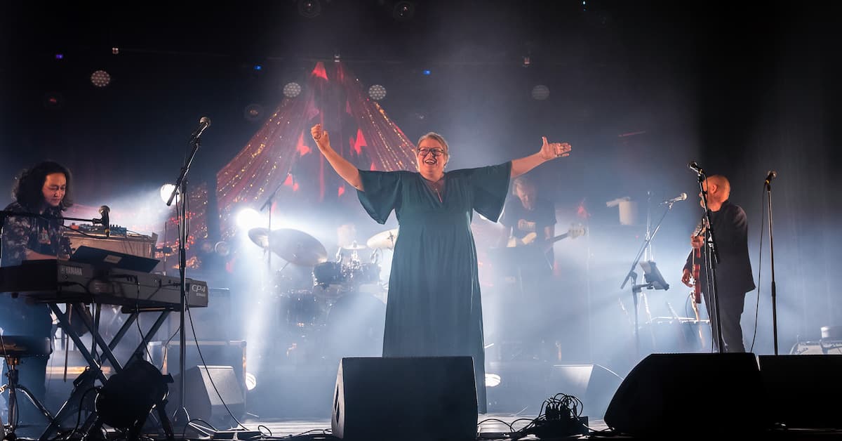 Marit Gjeset på scenen Kvinne stående midt på en scene omringet av en keyboardist, en trommis og en bassist