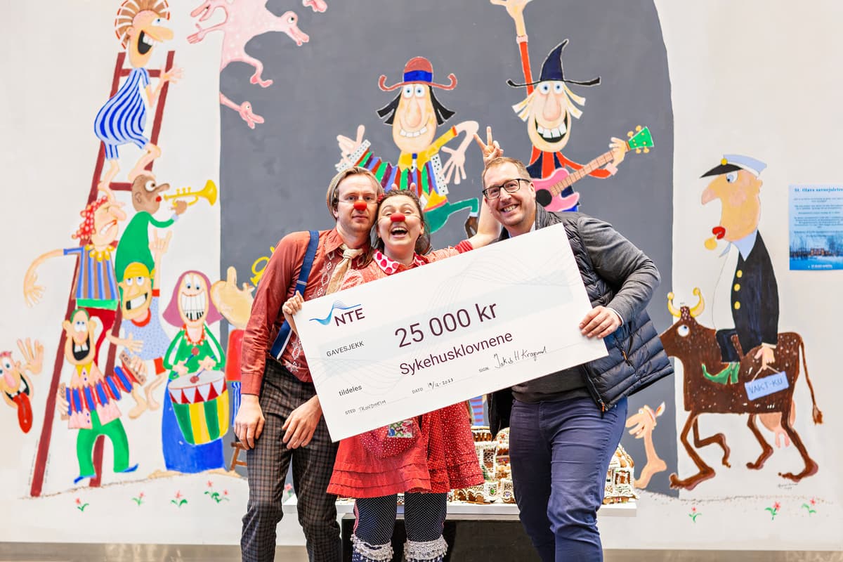 klovner og jakob med sjekken To klovner og en mannlig NTE-ansatt holder en sjekk på 25 000 kroner mellom seg