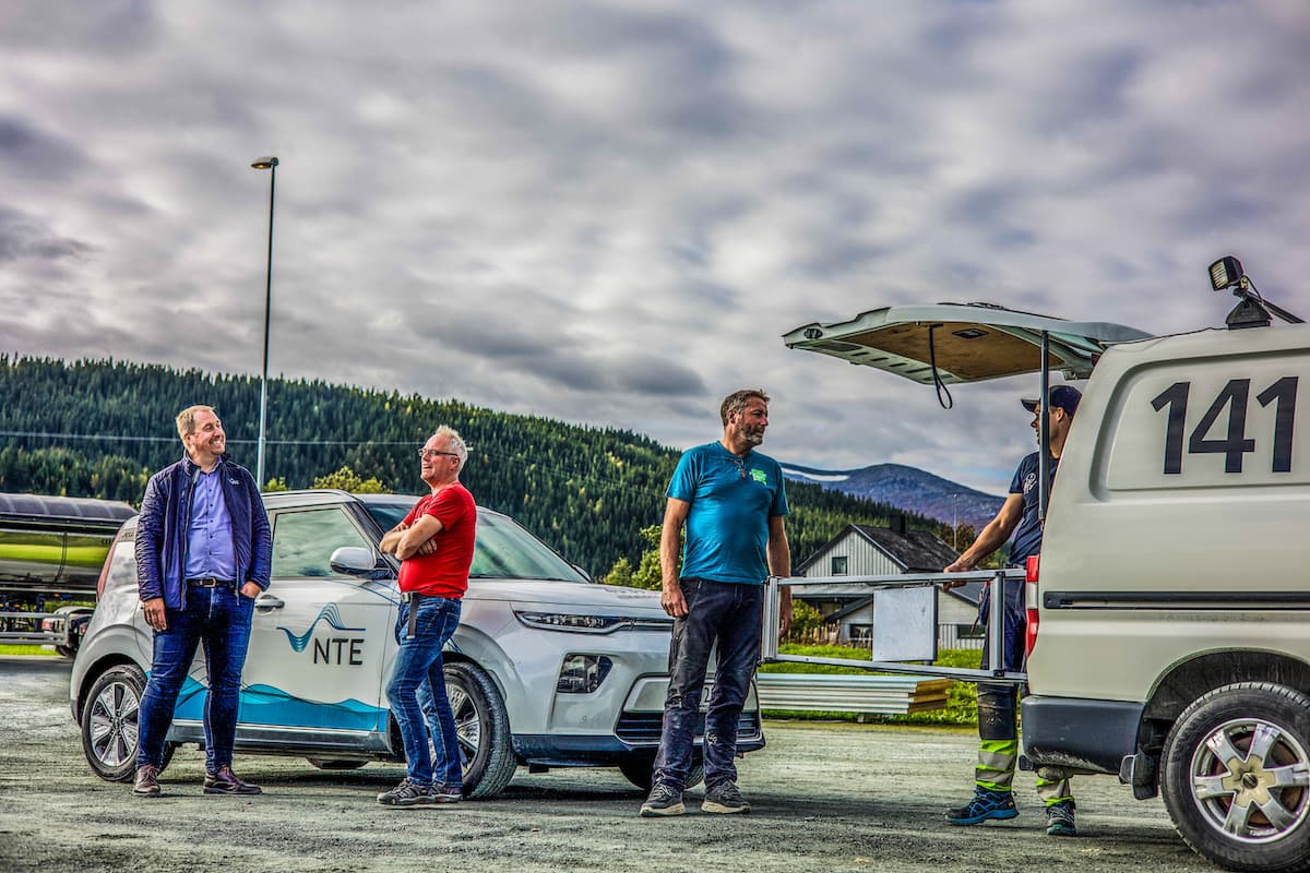 samarbeid Fire menn og to biler med NTE-logo på