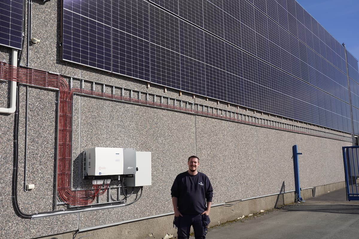 montøren Smilende elektriker foran solcelleanlegget