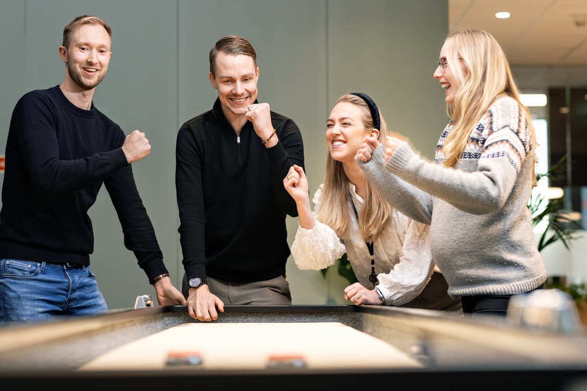 Kollega spiller shuffleboard To kvinner og to menn spiller shuffleboard og jubler