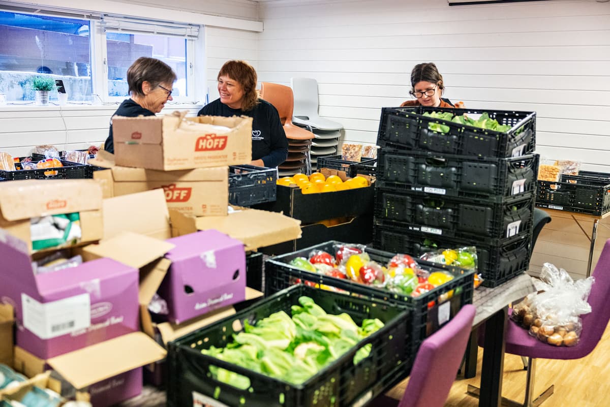 Frivillige i gang med pakking av matkasser Tre damer pakker ulike matvarer ned i kasser. Foto.