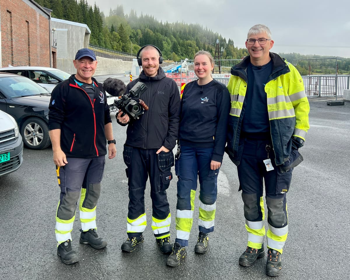 Filmteam og NTE-ansatte i gang med innspilling av TV-serien Spenningens helter Fire personer står oppstilt og smiler. Den ene har et filmkamera. Foto.