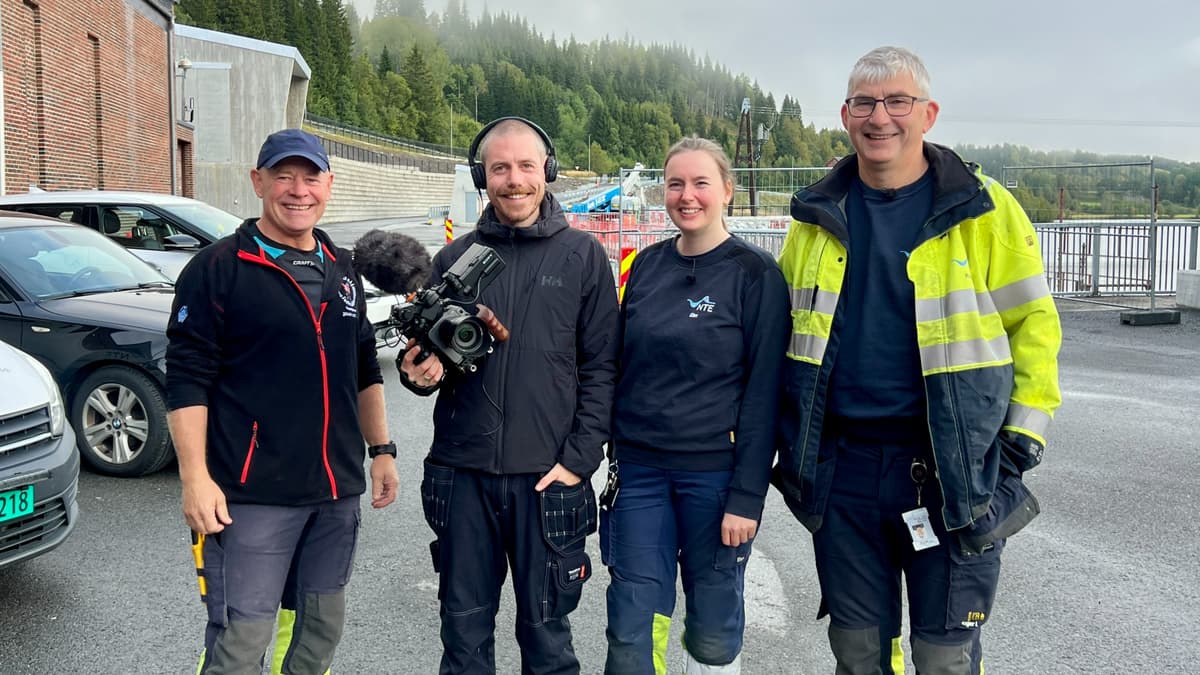 Filmteam og NTE-ansatte i gang med innspilling av TV-serien Spenningens helter Fire personer står oppstilt og smiler. Den ene har et filmkamera. Foto.