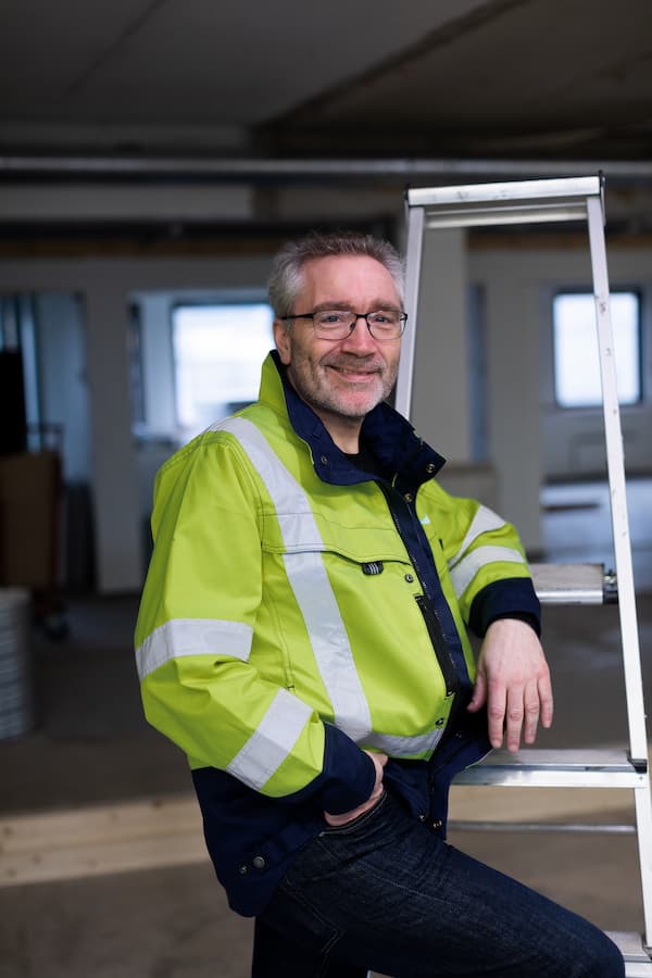 Ketil Berg 2 Smilende mann lener seg inntil en gardintrapp