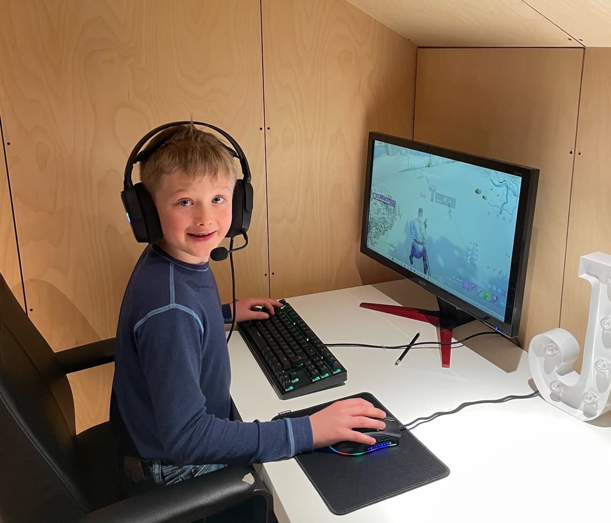 Gutt sitter foran pc-skjerm med hodetelefoner og spiller dataspill Gutt sitter foran pc-skjerm med hodetelefoner og spiller dataspill
