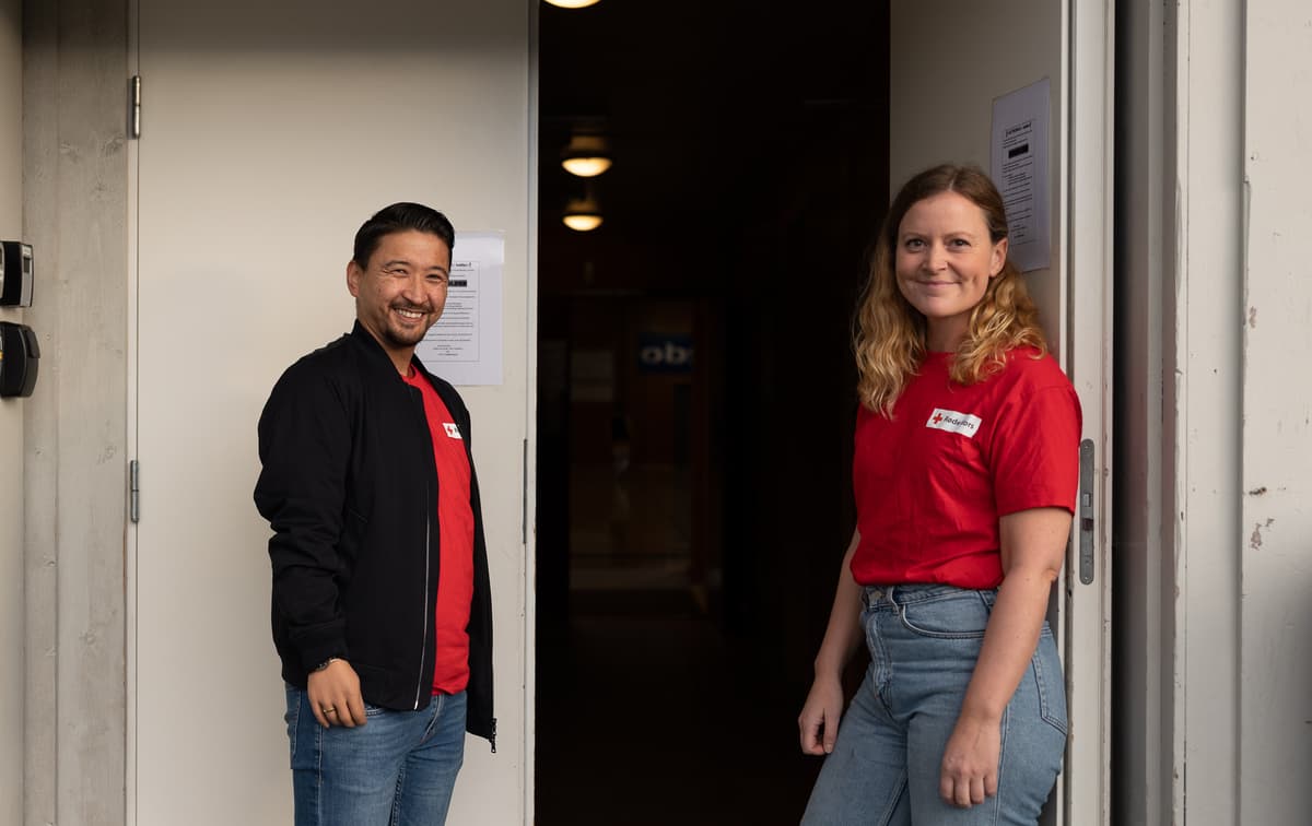 Fotballgruppa Mann og kvinne står i døråpningen og smiler