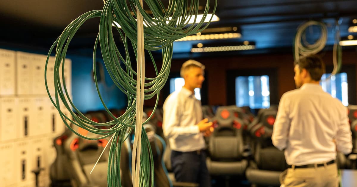 Fiberkabler Rull med fiberkabler i fokus med to menn som snakker sammen i bakgrunnen