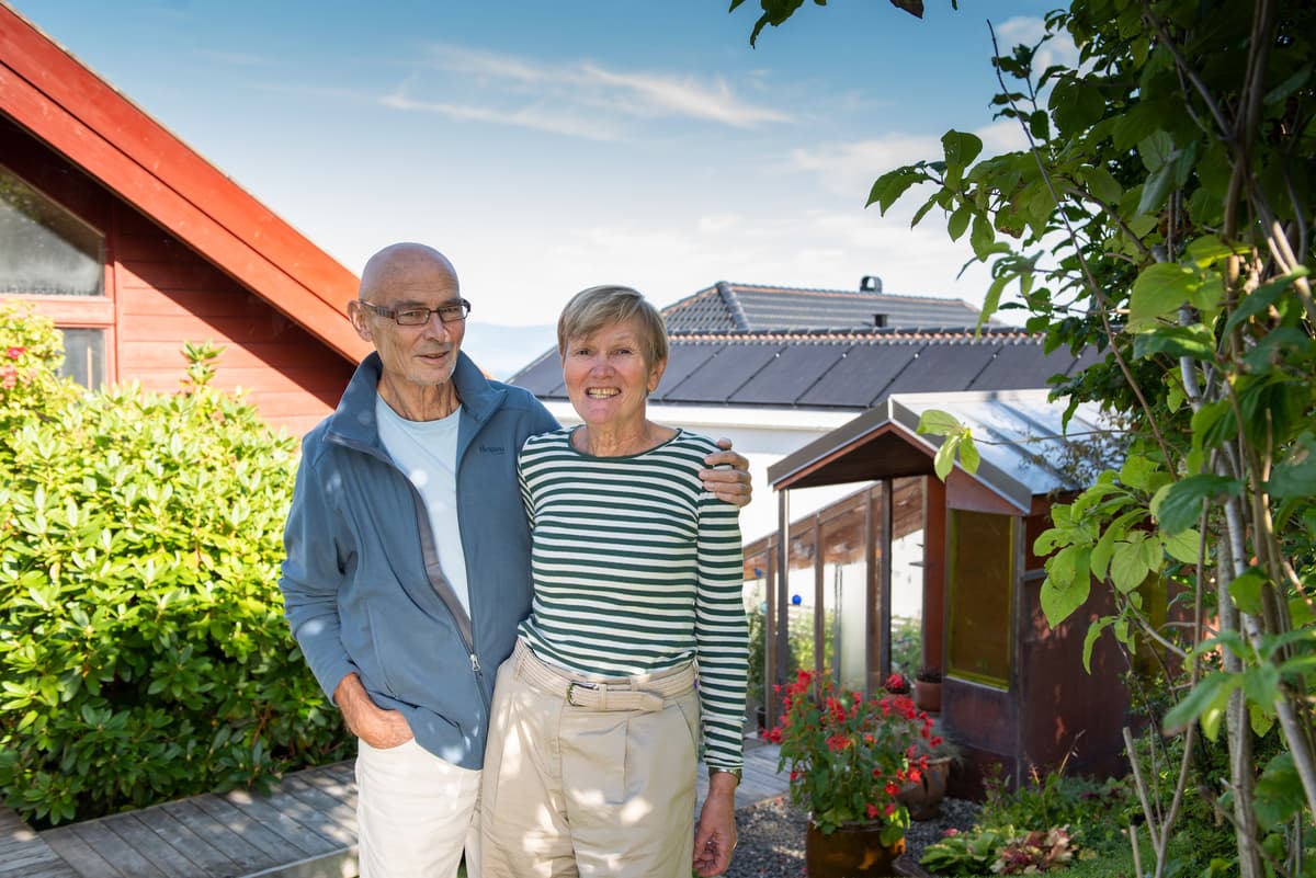 Smilende mann holder rundt en smilende og dame i en hage Smilende mann holder rundt en smilende og dame i en hage