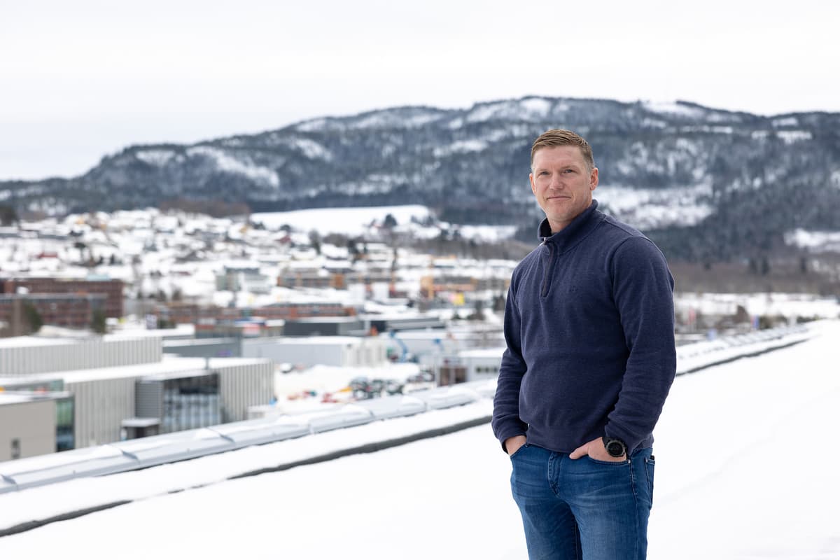 Morten oksnes NTE2 Mann på et tak med fjell og bygninger bak