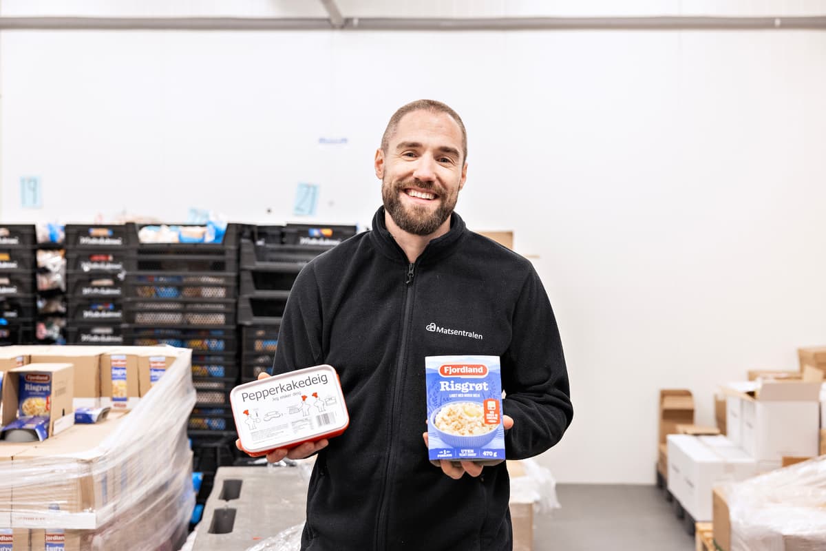 jort med julevarer Smilende mann som holder opp en pakke pepperkakedeig og en pakke risgrøt