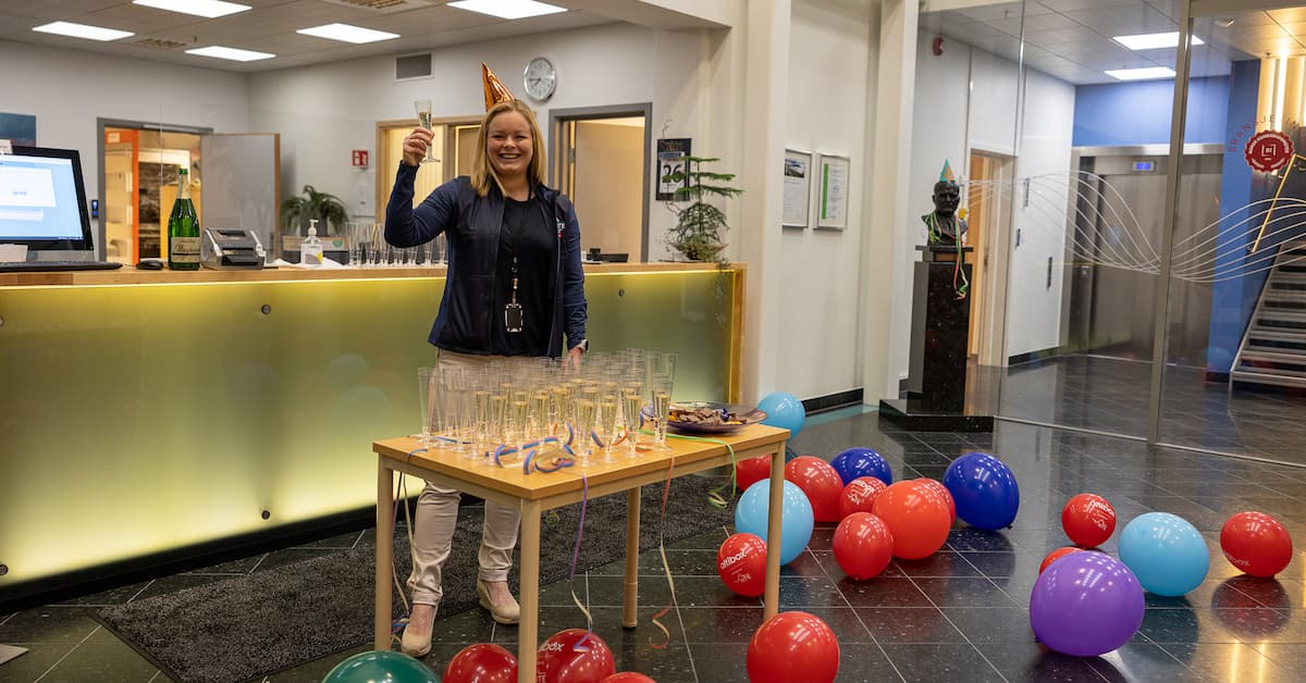 Nina Arnesen Smilende dame med partyhatt som serverer brus og sjokolade omgitt av ballonger